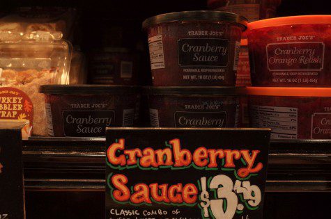 Several cans of red cranberry sauce stacked in a layer on a shelf with a tag that says 