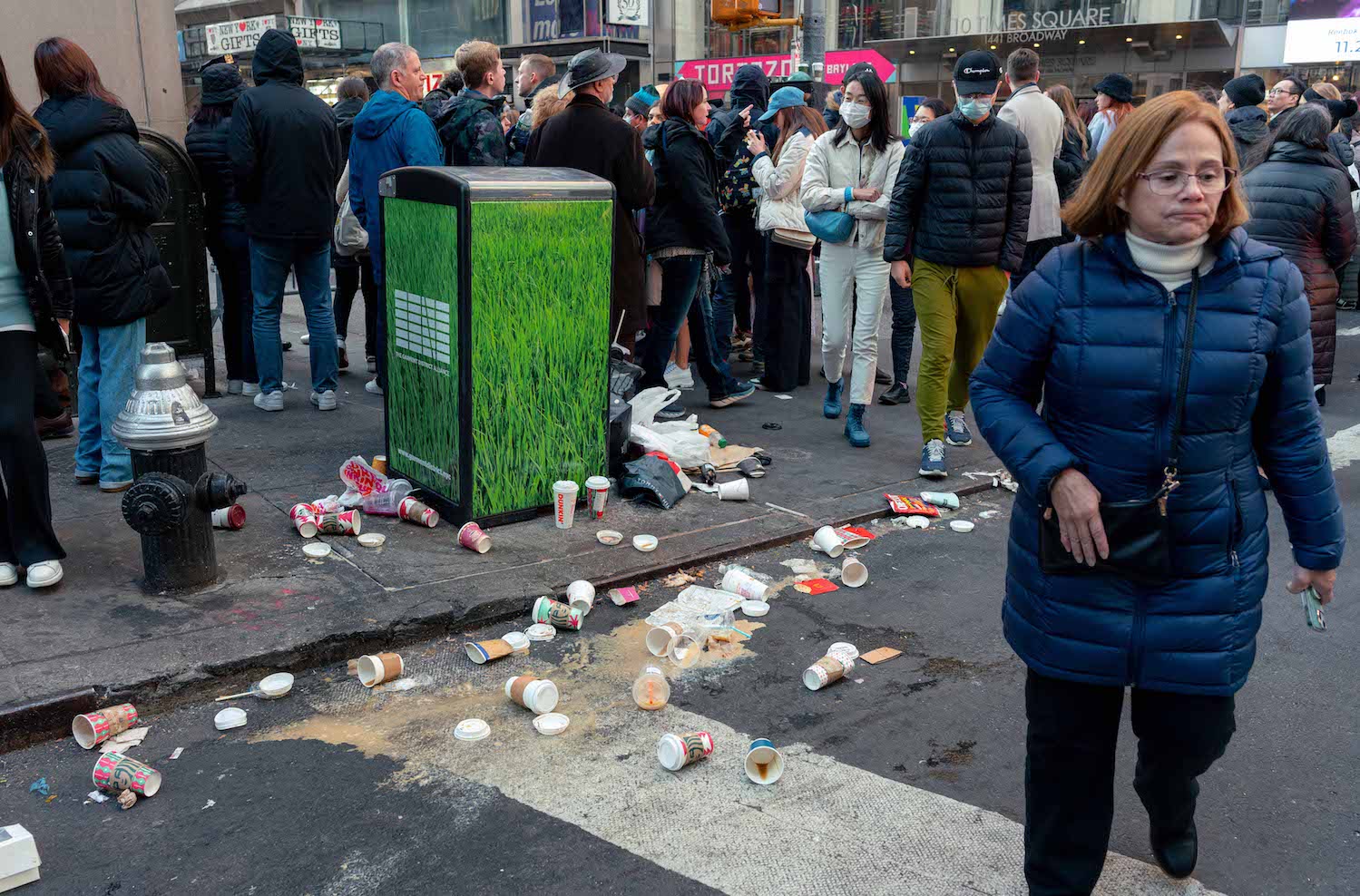 Holiday-themed Starbucks paper cups and other trash were left on the sidewalk as trash cans overloaded.