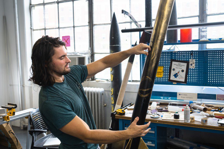 Alex Miller examines the gold and black paint on his rocket.
