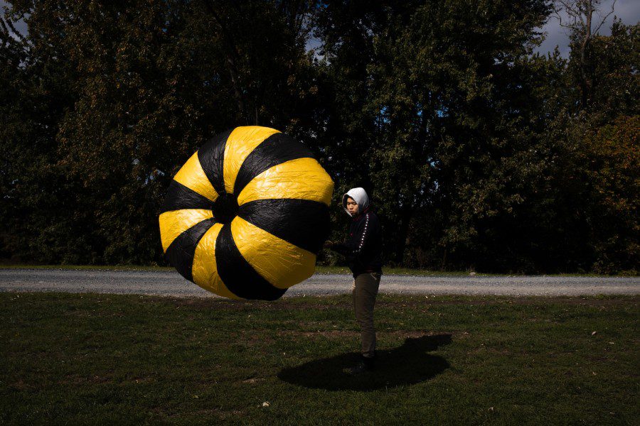 Alx Xu inspects the integrity of his yellow-and-black striped parachute.