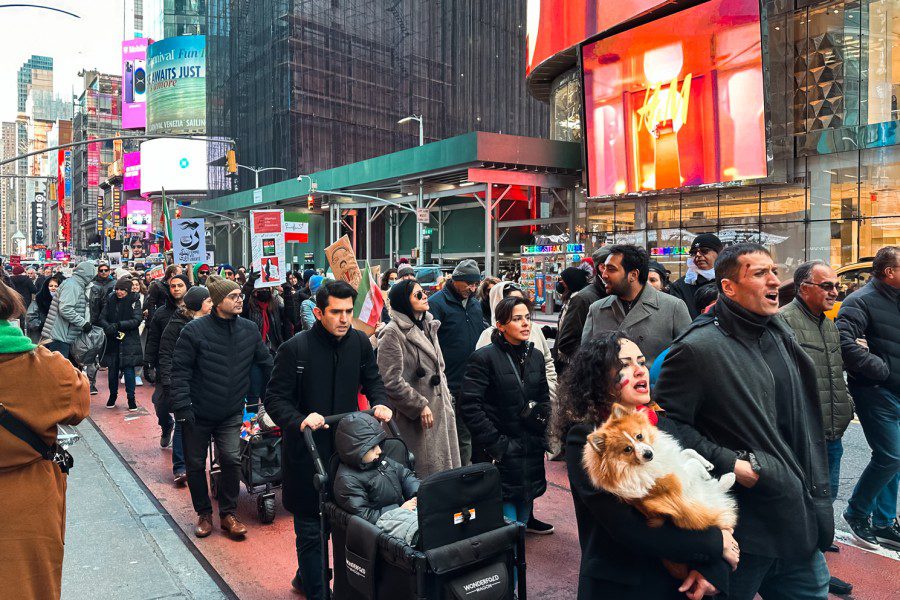 A group+of+protesters+marches+along+Seventh+Avenue+near+Times+Square.+Some+of+them+hold+posters+with+the+Iranian+flag+on+them.