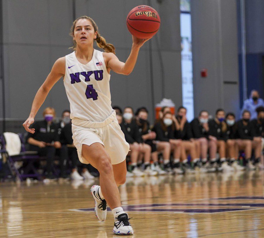 Belle Pellecchia, the NYU women’s basketball team’s guard, holds a basketball in one hand while running.
