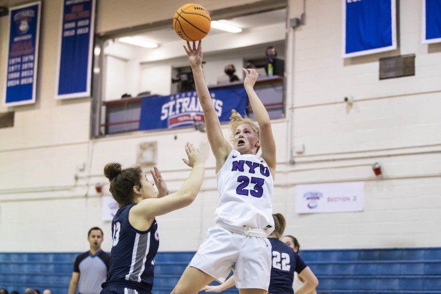 Jenny Walker, number 23, shoots a jump shot wearing a white jersey and shorts as an opponent player dressed in black tries to block her.