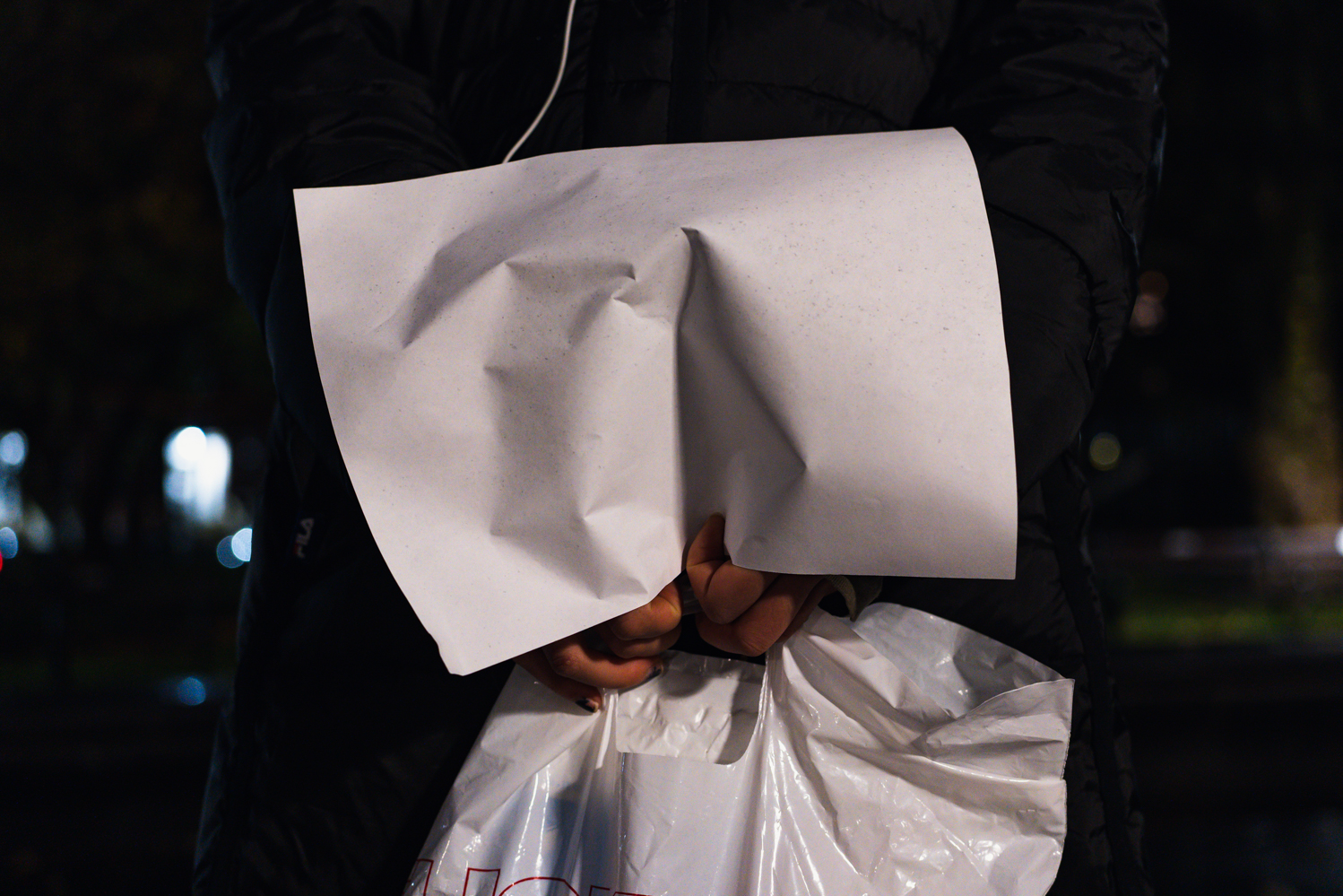 A pair of hands tightly gripping a piece of white paper.