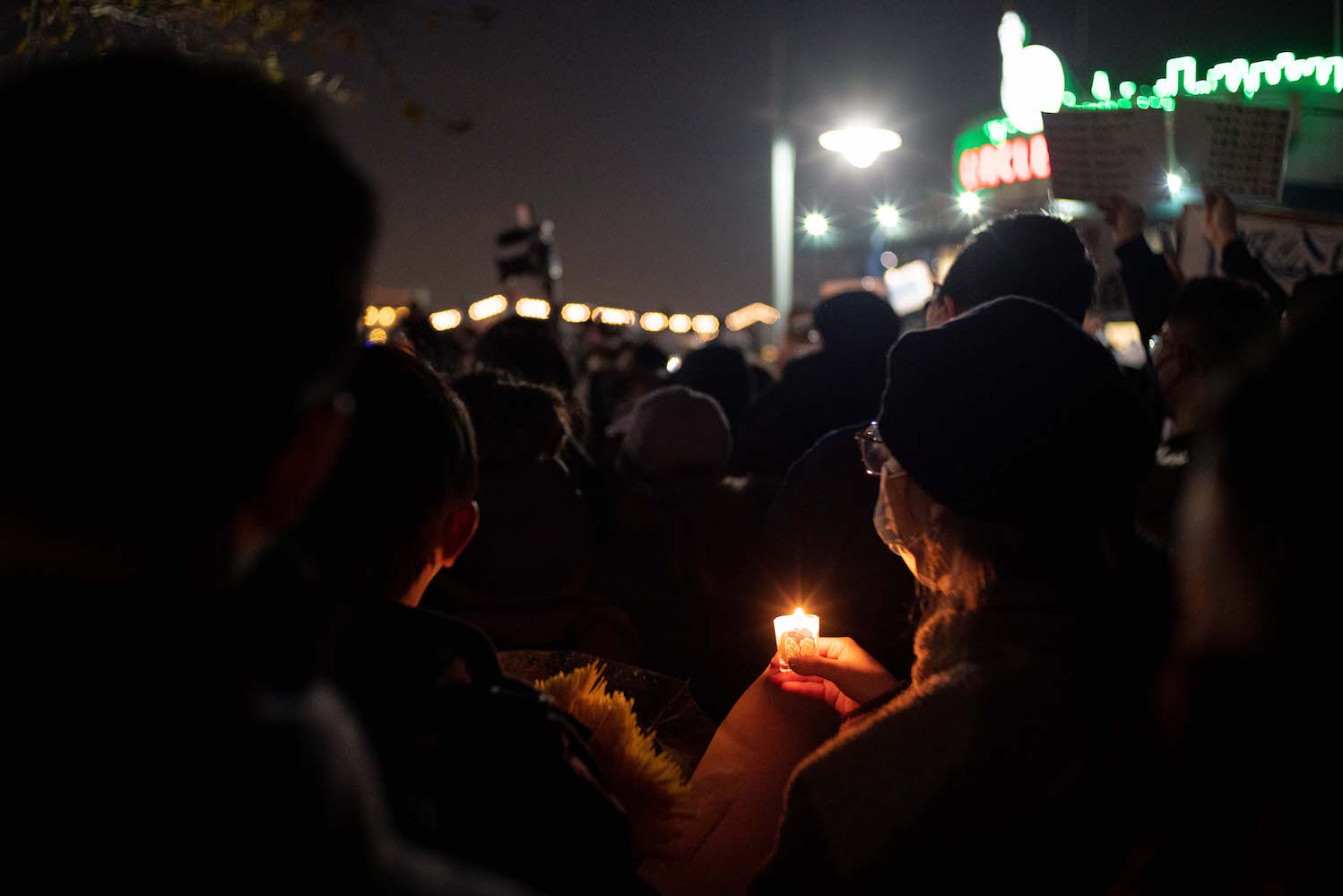 A couple holds a candle between their hands while participating in the protest in the dark.