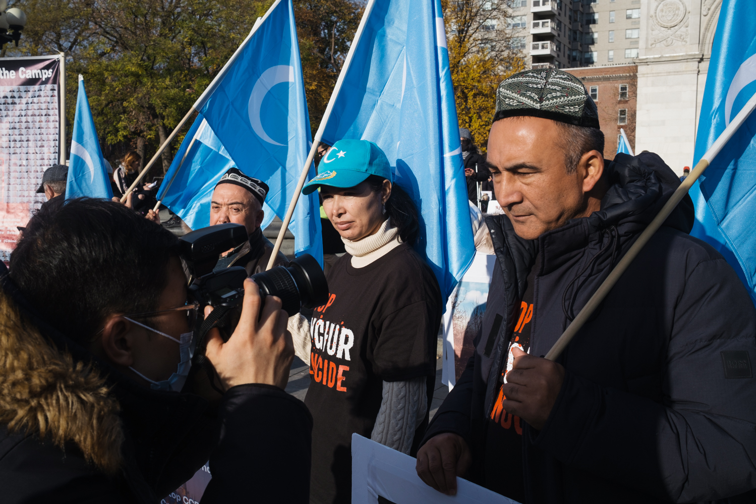 A photographer capturing the faces of Uyghur protesters who wave the light blue flags — with a white crescent moon and star — of East Turkestan.