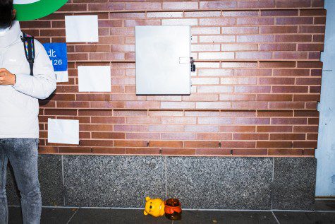 A Winnie-the-Pooh jar with the cap detached lies on the ground against a brick wall. A protester stands to the side.