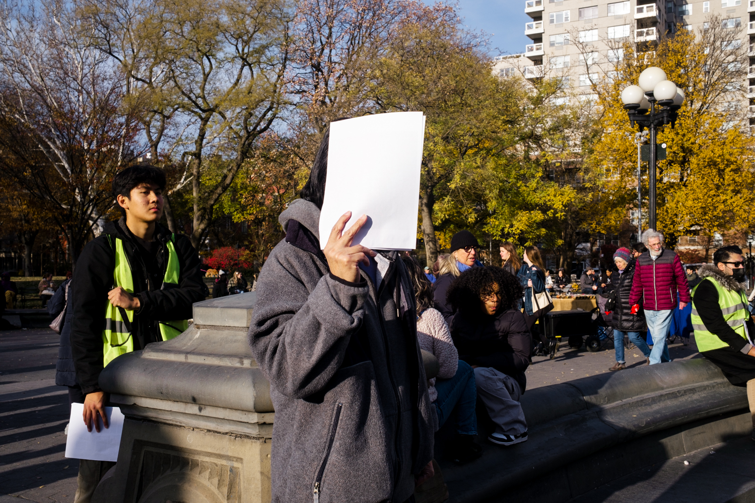 A protester covers their face with a sheet of white paper.