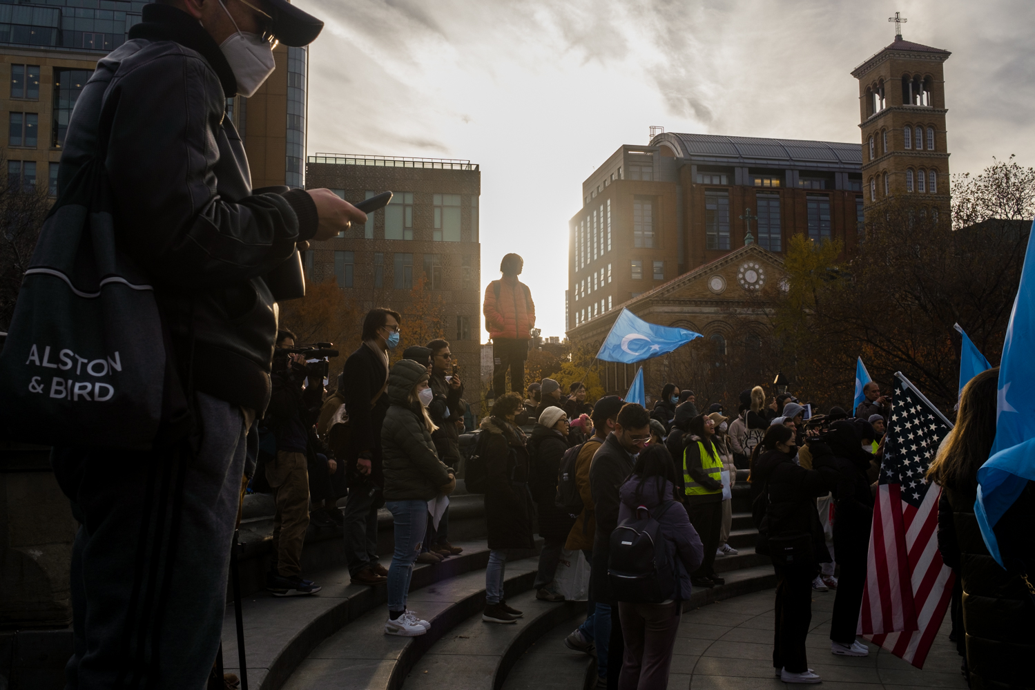 A group of protesters standing in the fountain at Washington Square Park. A person stands on the edge of the fountain.