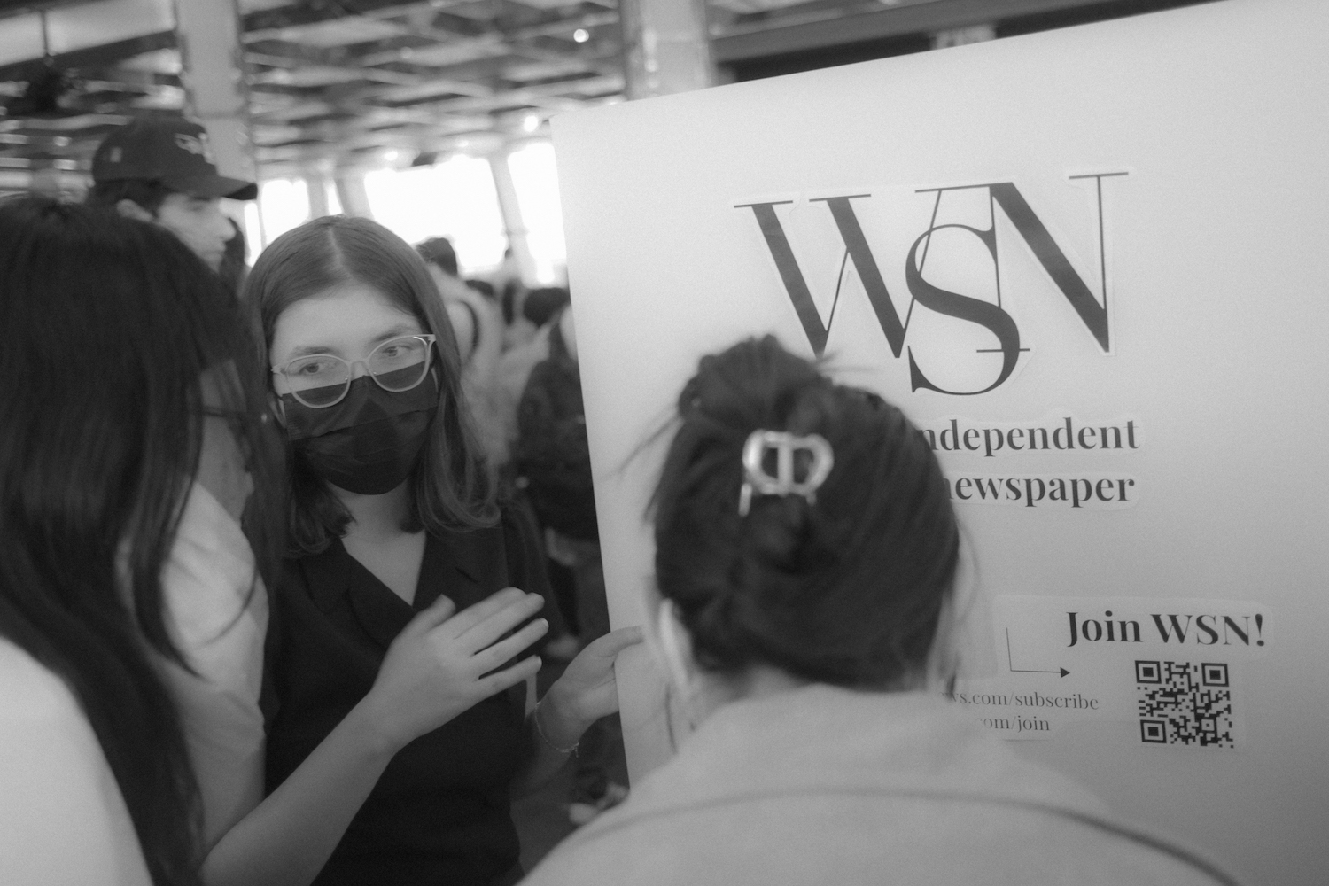 Susan Behrends Valenzuela, wearing a black shirt and a black mask, talks to N.Y.U. students at the Club Festival.