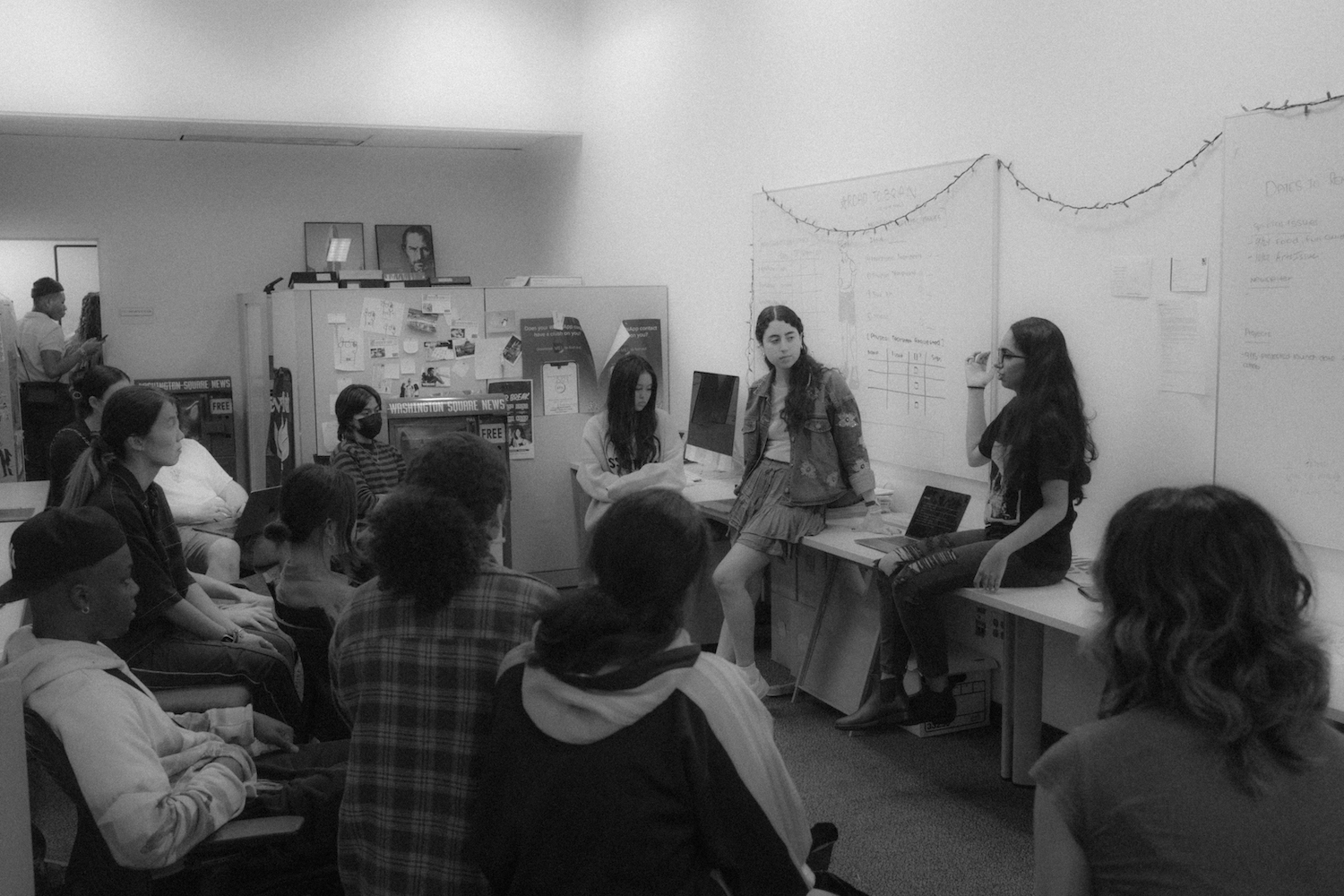 Camila Ceballos and Manasa Gudavalli hold a meeting with photographers and editors in the office corridor.