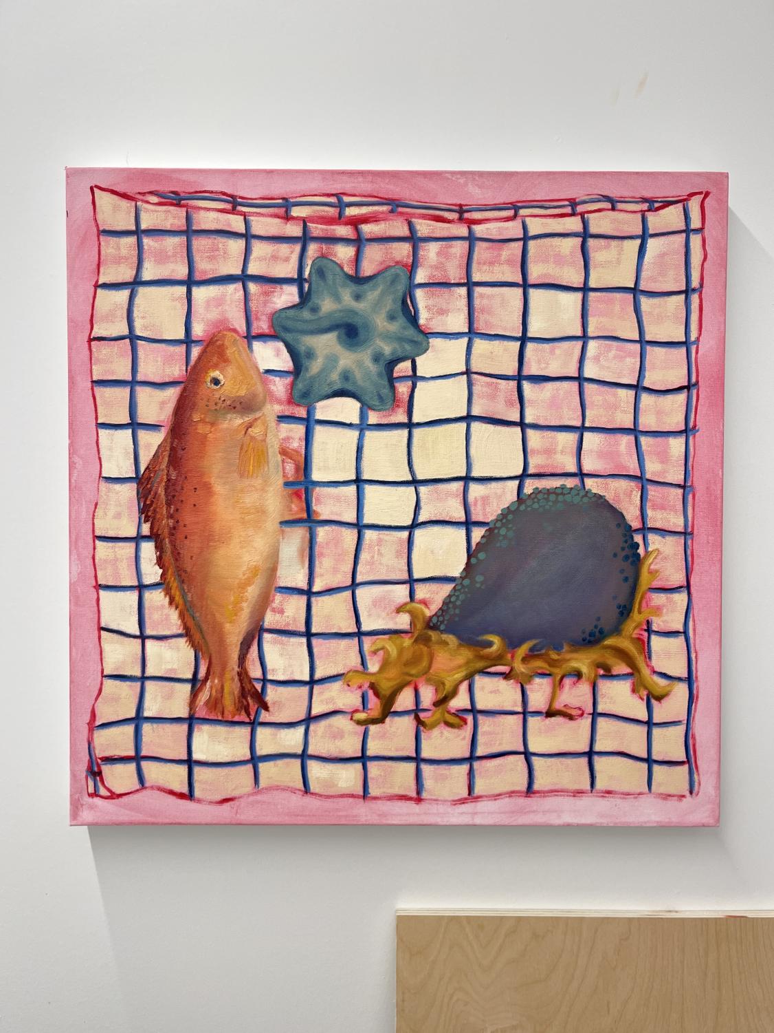 An oil painting with a pink gridded background showing an orange fish, a blue starfish, and a dark blue-and-orange ambiguous sea creature. The painting hangs on a white wall, with the top left corner of a brown board in the bottom right corner of the image.