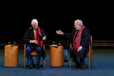 ill Clinton and John Sexton, both wearing black robes with red stoles, sit for a panel discussion.