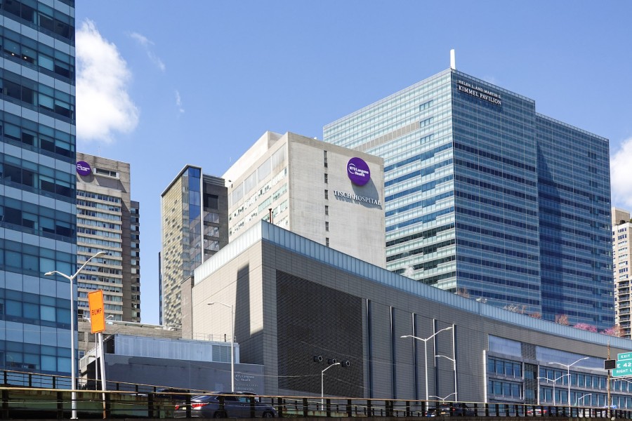 A tall hospital building complex with three towers that display purple N.Y.U Langone Health logos.