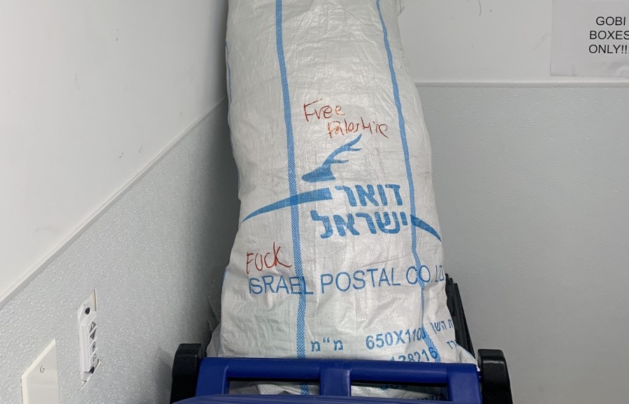 A white mail bag with blue text reading “Israel Postal Co. L.T.D.” on it. “Fuck” and “Free Palestine” are written with red marker on top.