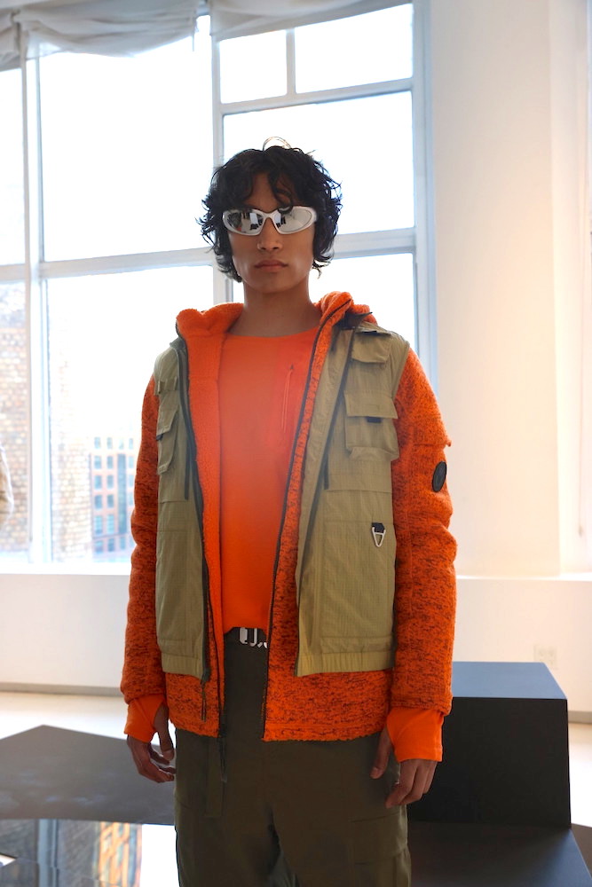 A model wearing an orange outfit and sunglasses at the C.E.M. show.