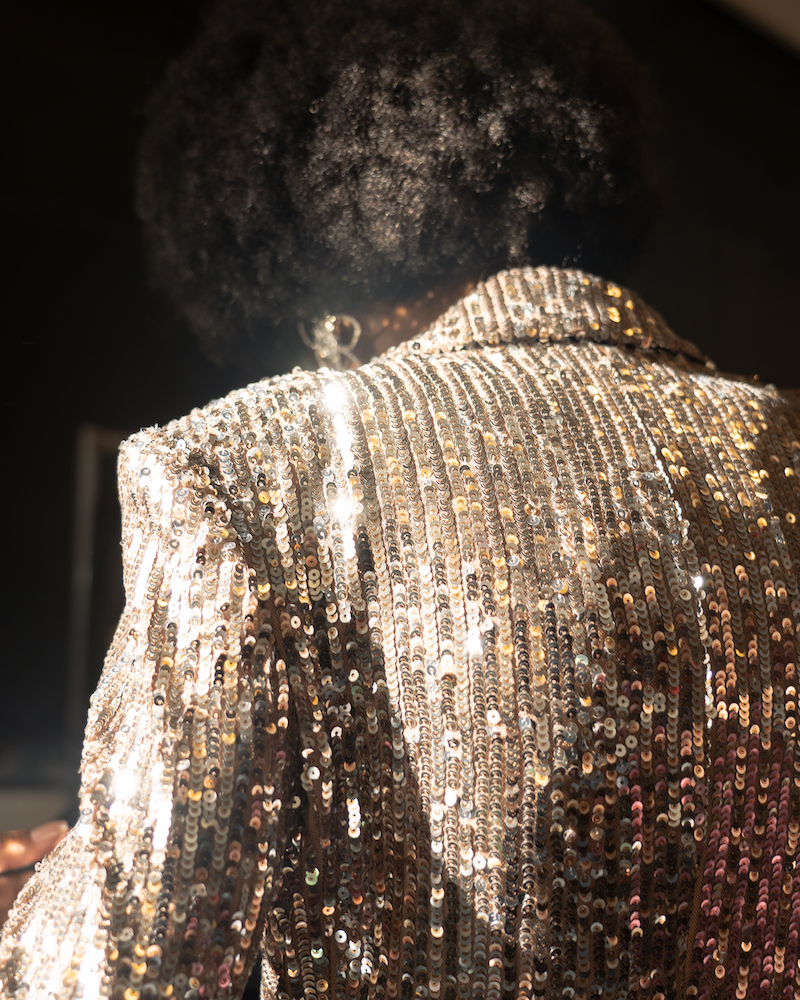 A photograph of the back detailing of a sparkly, silver top, illuminated in the sunlight.