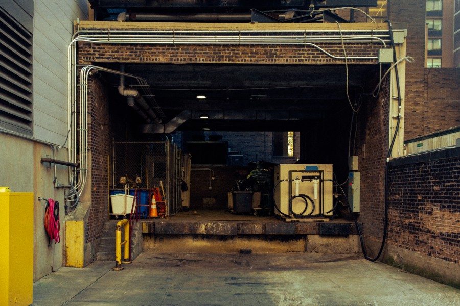 A cargo loading dock with maintenance equipment and trash cans inside.