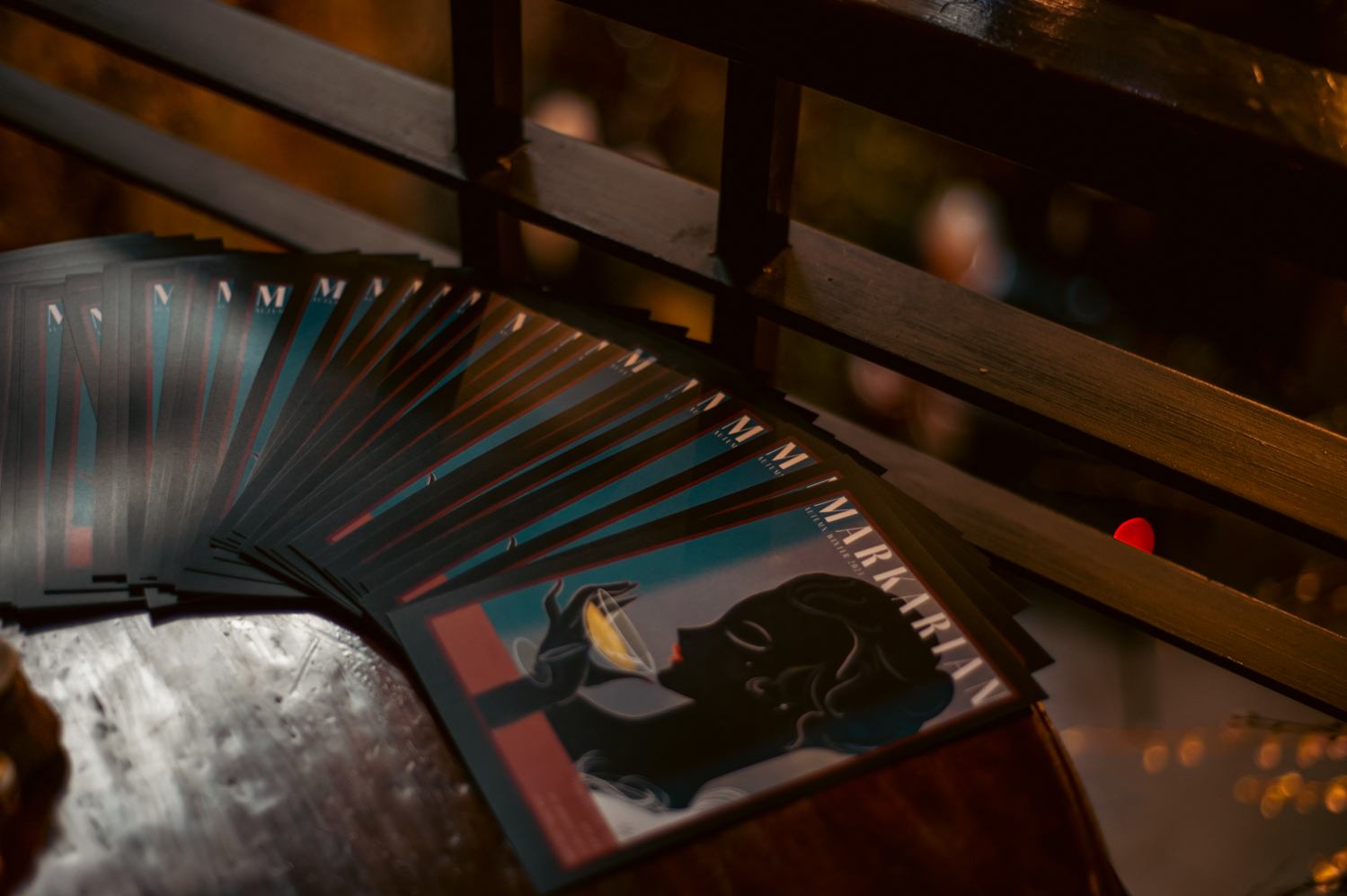 Flyers reading “Markarian” show a woman sipping from a martini glass, and are fanned out across a wooden table.