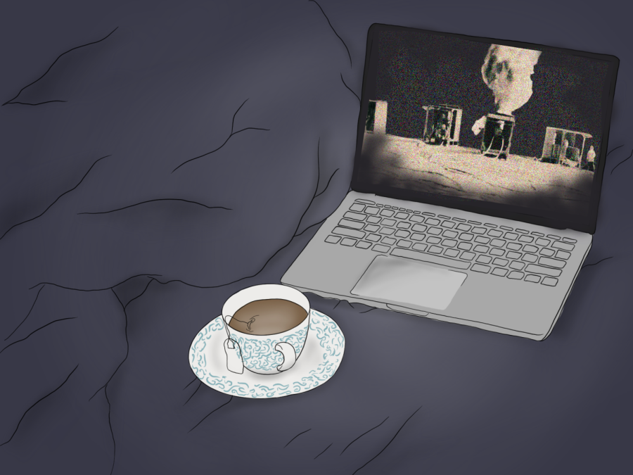 A cup of coffee and a laptop screening a monochrome image of building compounds on fire in a desert on top of a gray blanket.