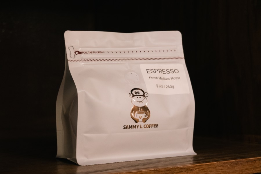 A small, white bag of coffee beans with a logo depicting a monkey and the words “Sammy L. Coffee.”