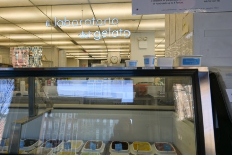 The counter of an ice cream shop with a blue neon sign hanging above that reads “il laboratorio del gelato.”
