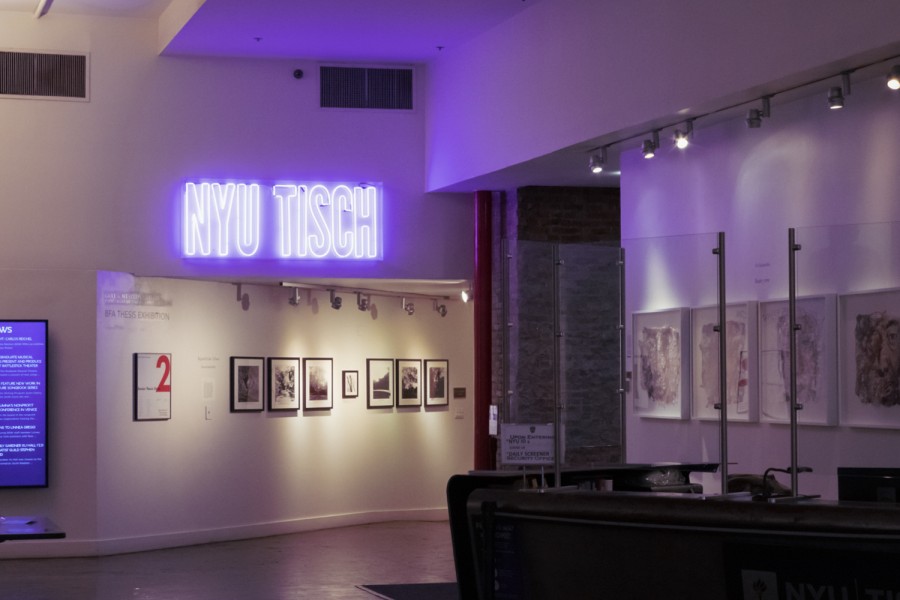 The interior of the N.Y.U. Tisch School of the Arts building. “N.Y.U. TISCH” is displayed on the wall in purple L.E.D. lights.