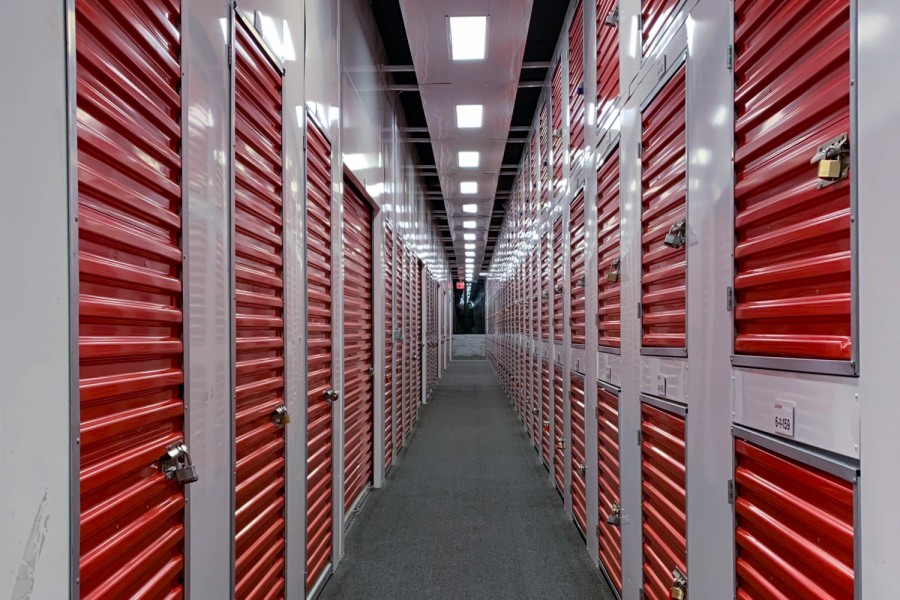 Two tall rows of storage units of different sizes. The doors to the units are red and locked.