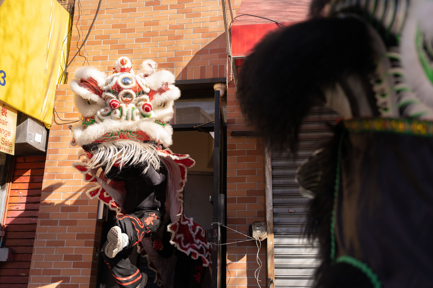 A lion dance performer marched out of a building with red bricks.