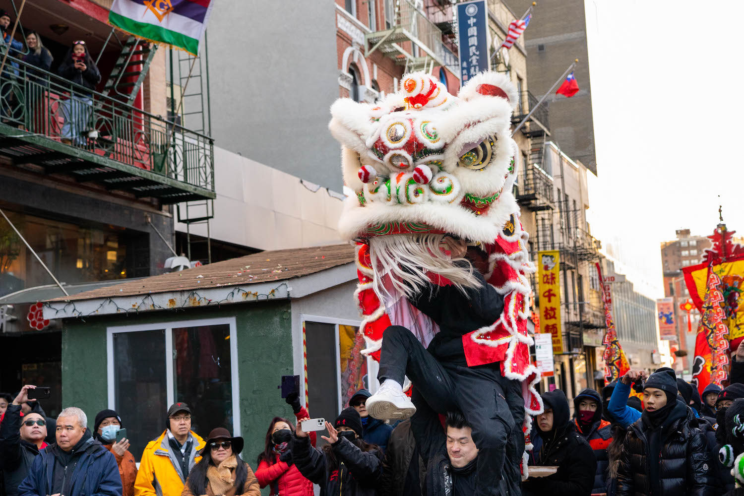 A lion dancer lifting his partner to make the lion costume rise during a performance.