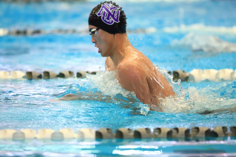 A photo of a swimmer wearing a swim cap and goggles swimming in a pool.