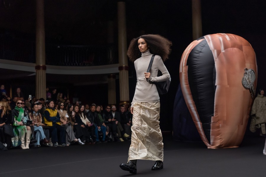 A+model+in+a+gray+turtleneck+and+a+white+skirt+who+is+holding+a+black+shoulder+bag+at+the+2023+E.E.N.K.+Paris+Fashion+Week+show.