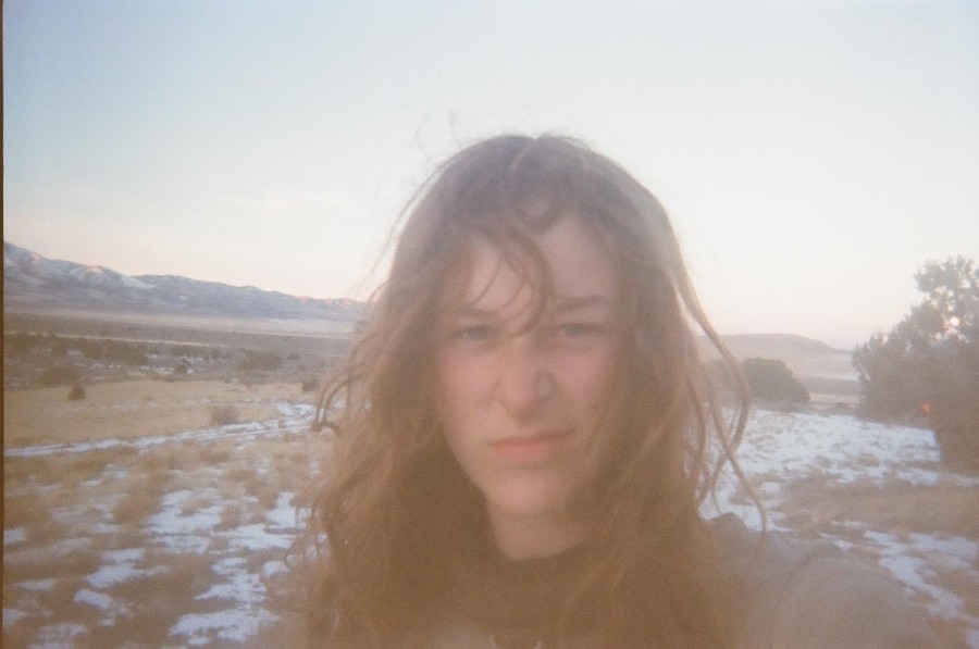 Ella Briggs looks at the camera as they take a selfie in front of the desert landscape behind them.
