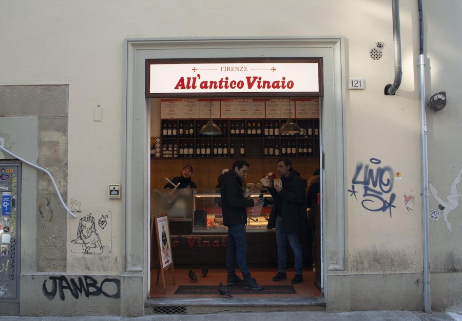 The gray storefront of a sandwich shop. On top is a white sign with red text that reads “Firenze All’antico Vinaio.”