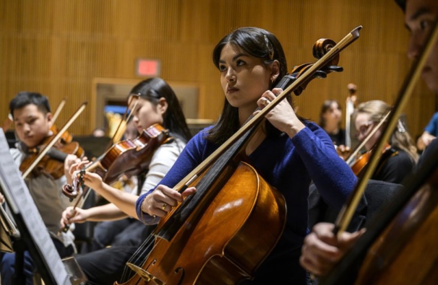 Noelia Carrasco plays the cello wearing a dark blue sweater.