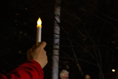 A hand holding an electric candle in the dark.