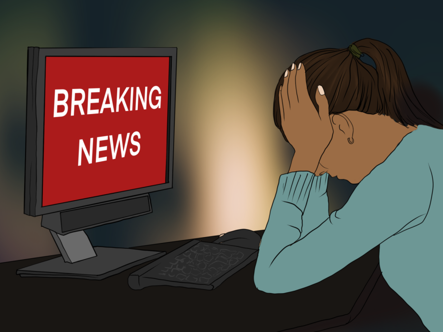 A person puts their elbows down as they cover their face in frustration. The monitor in front of them displays “breaking news” in white text against a red background.