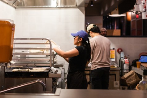 A worker at Forsyth Fire Escape, wearing a blue cap and a black shirt, prepares dough.