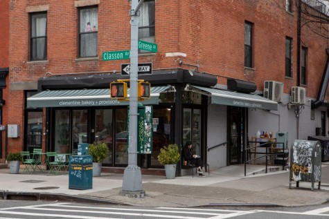 The storefront of a bakery at a street corner. The bakery is located inside a building with a red brick exterior.