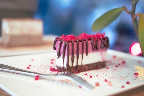 A slice of chocolate and berry cake on a plate with a fork next to it.