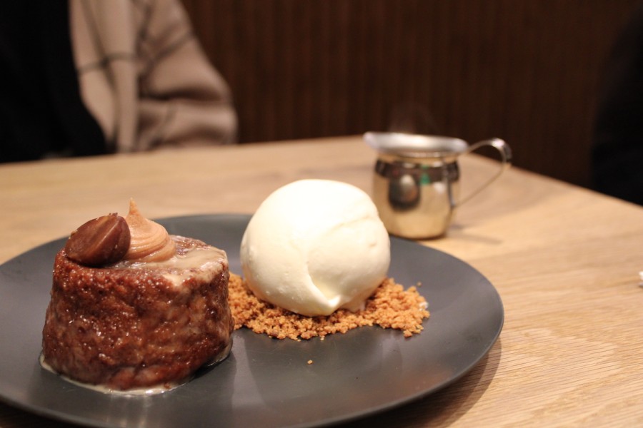 A blue plate on the table with a cake and an ice cream ball.