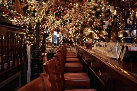 The interior of a restaurant with a bar counter and many yellow string lights hanging from the ceiling.
