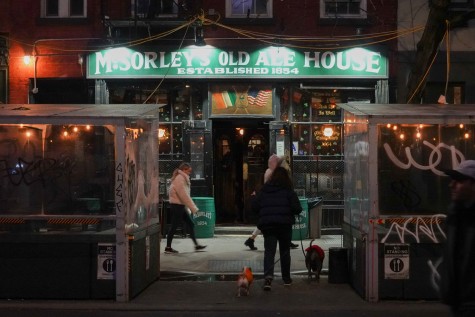 The exterior of a bar with green signage that reads “McSorley’s Old Ale House.” Above the entrance are the drawings of the Irish flag and the U.S. flag.