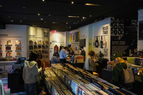 The interior of record store "Rough Trade." Customers browse through vinyl records on wooden tables.