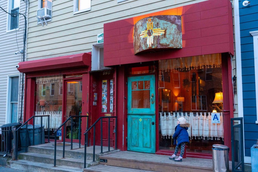 The exterior of Santa Fe B.K. with crimson window frames and walls and a turquoise door.