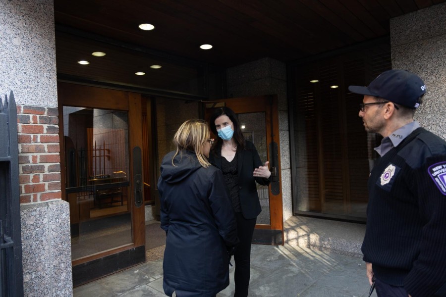 Michelle Cherande, dressed in all black and wearing a mask, speaks to a woman outside the DAgostino Hall.