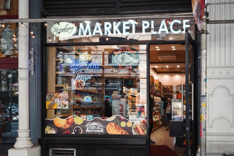 Photograph of a delicatessen. Signage on the window reads “Broadway MARKETPLACE.”