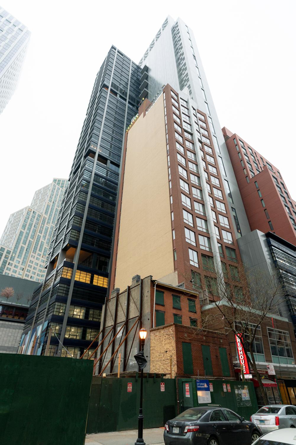 227 Duffield St. is seen beside towering modern apartment buildings.