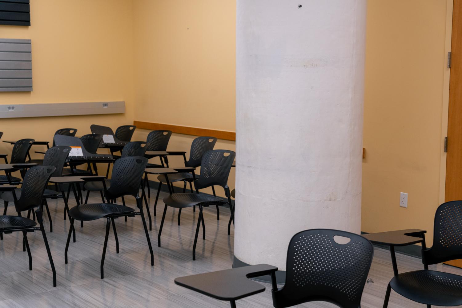 A large, white pillar divides chairs with attached desks in a Rogers Hall classroom.