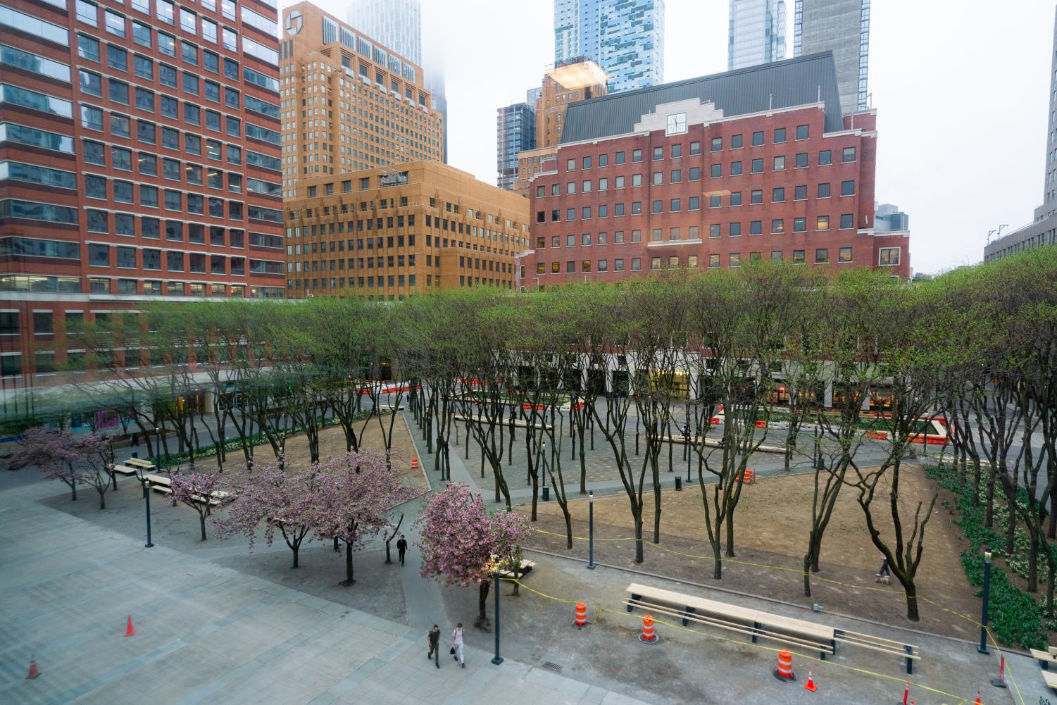 A small park appears nestled between various MetroTech buildings. The buildings share similar architectural styles of warm-toned facades and a surplus of small windows. The photo is an aerial shot.